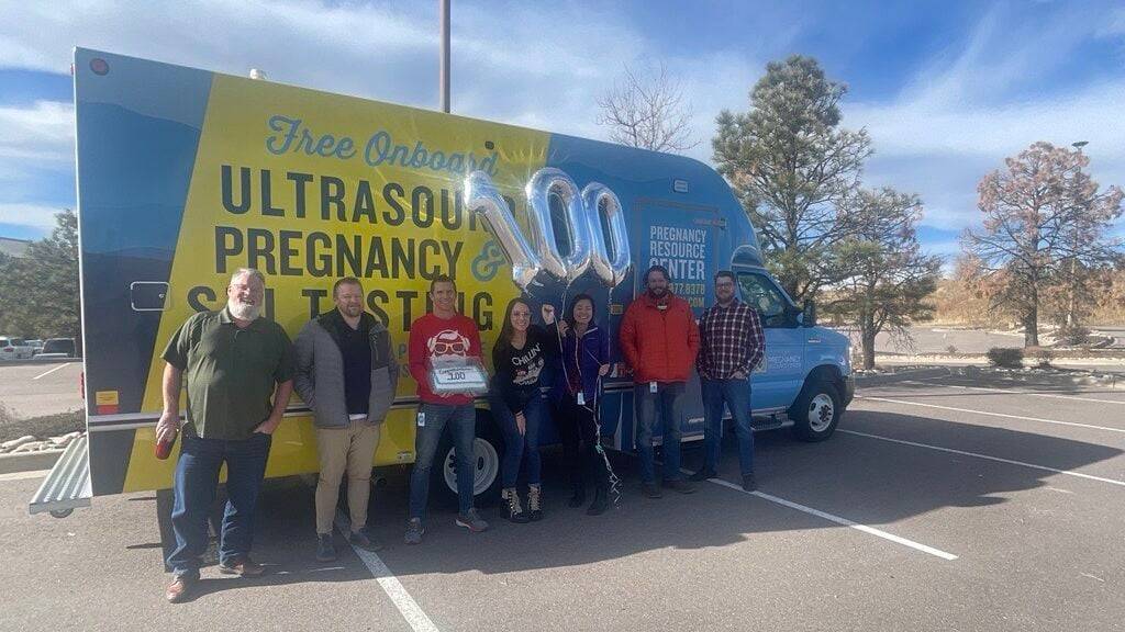 group of people standing in front of a Mobile Medical Clinic