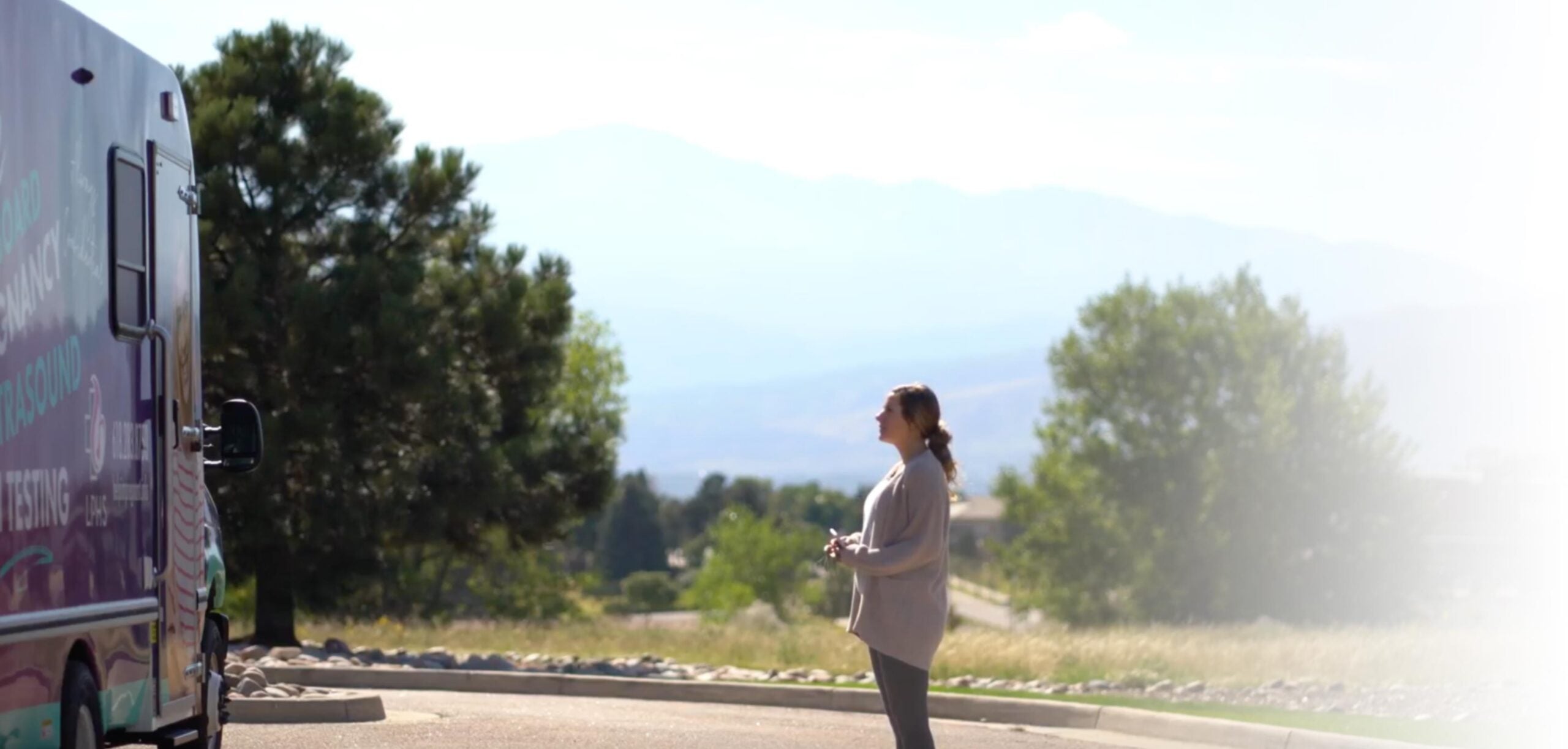 woman standing far from women's health bus looking toward the bus.