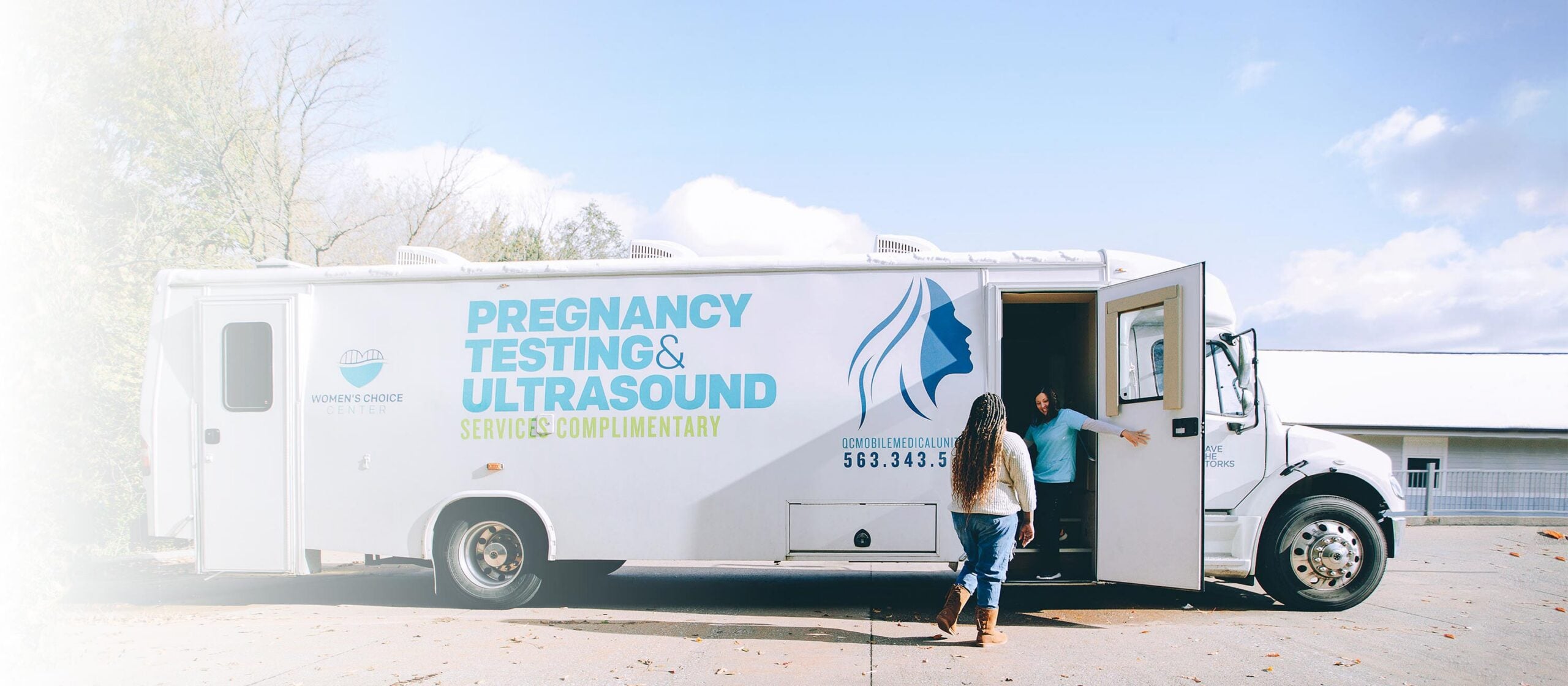 woman opening door of pregnancy testing and ultrasound bus to invite other woman inside.