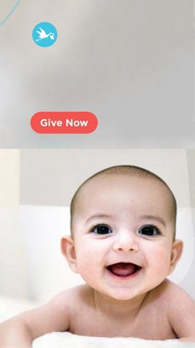 Baby on white carpet smiling at camera. Give Now
